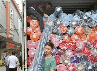 處于紡織商圈核心位置的廣州國(guó)際輕紡城，貨物裝滿車(chē)廂，工人忙著出貨。